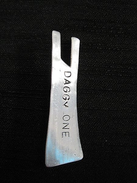 Daggy One brooch: Aluminium Black Singlet shape, stamped with the words "DAGGY ONE"